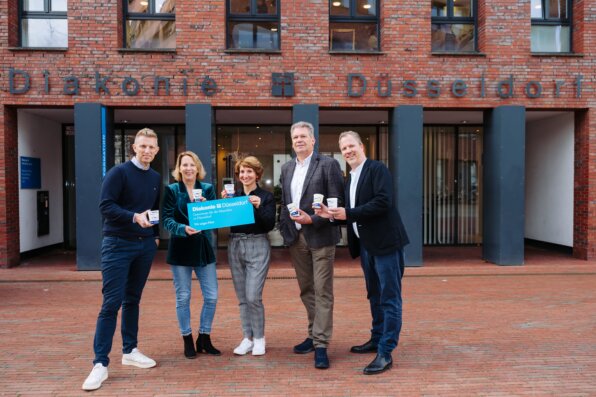 Foto: Von links nach rechts – Thomas Franken (Messe Düsseldorf), Sonja Laudin (Diakonie Düsseldorf), Dzenita Antunovic (Borealis), Philip Knapen (Borealis) und Mario Nickel (FORTESNICKEL) übergibt Mehrwegbecher an die Diakonie Düsseldorf